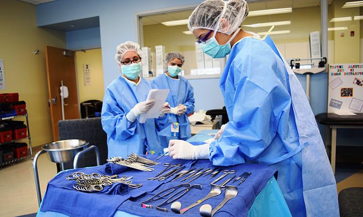 Surgical Tech 学生 work together in an operating room.